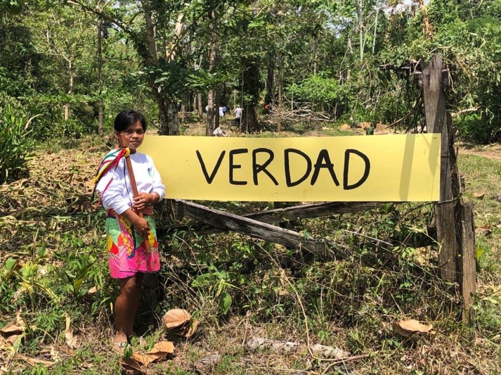 En kvinna utomhus intill en skylt med texten "Verdad".