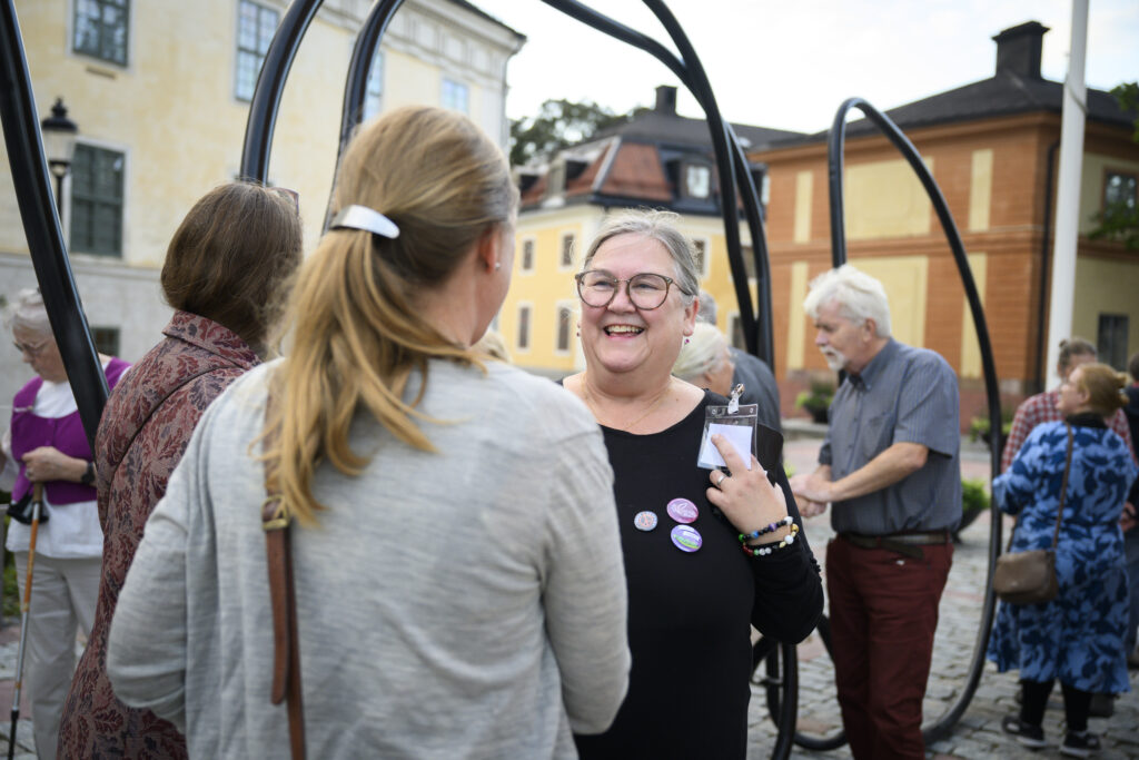 Personer ler och minglar vid en skulptur som formar ordet MOD.