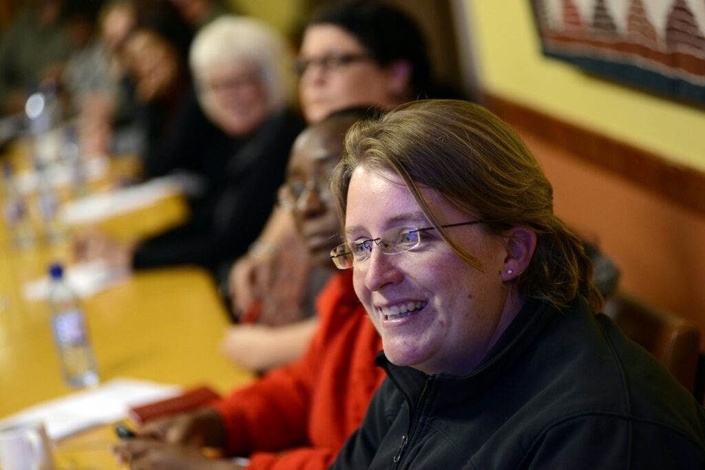 Bild på Charlene Van der Walt som sitter på möte med fler deltagare i bakgrunden.