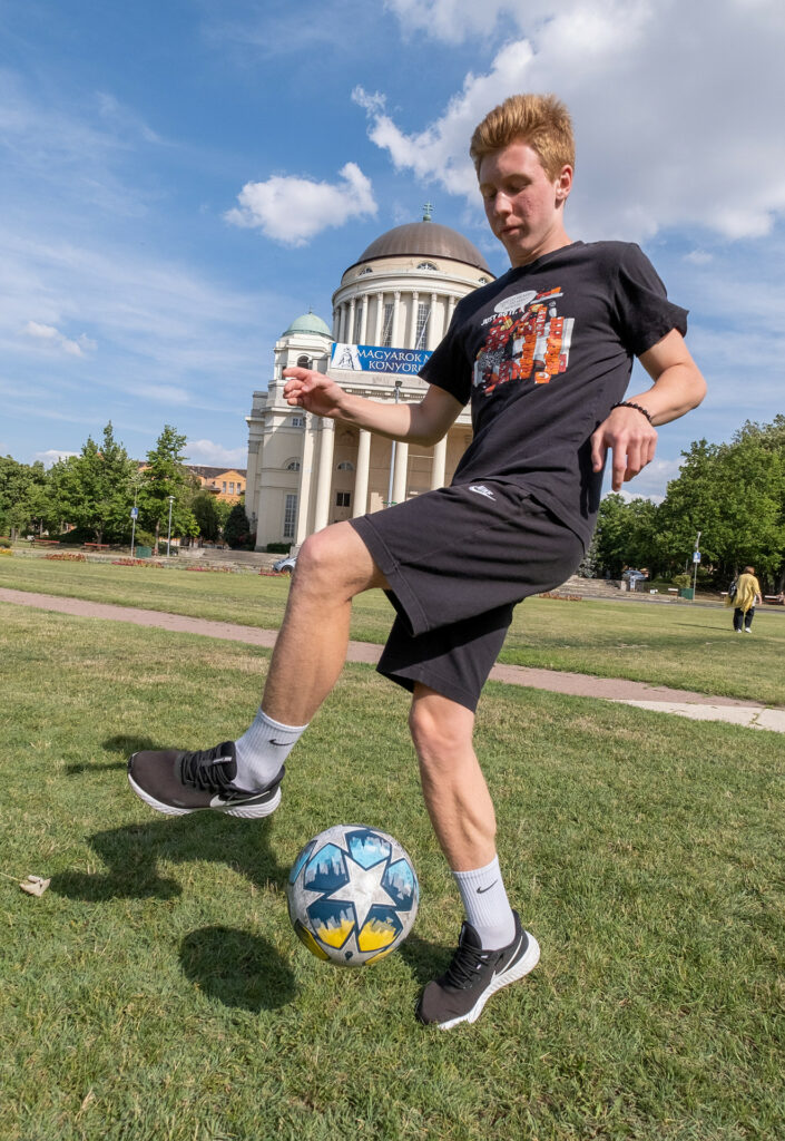 Tonårskille trixar med en fotboll på en gräsmatta.