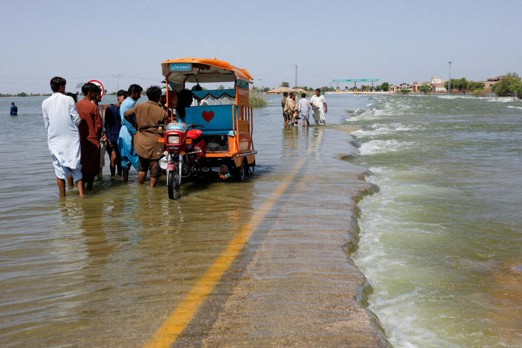 Displaced people stand on flooded highway