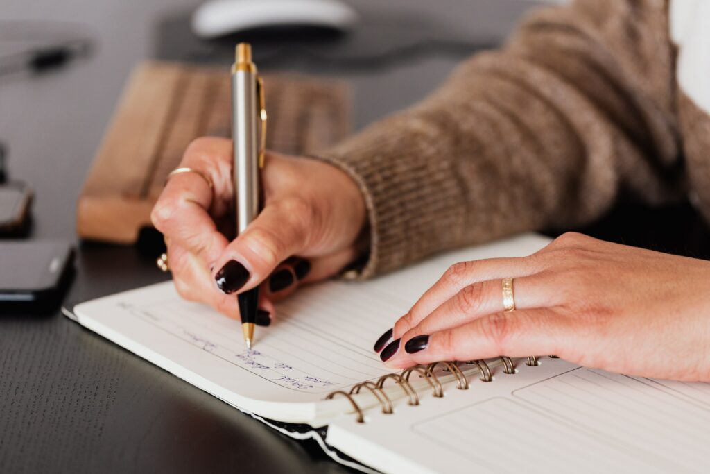 Närbild på ett skrivblock och en kvinnas händer som antecknar.