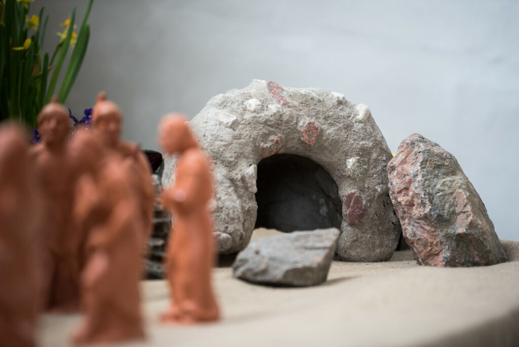 En grupp med små lerfigurer står framför en miniatyrgrotta av sten.