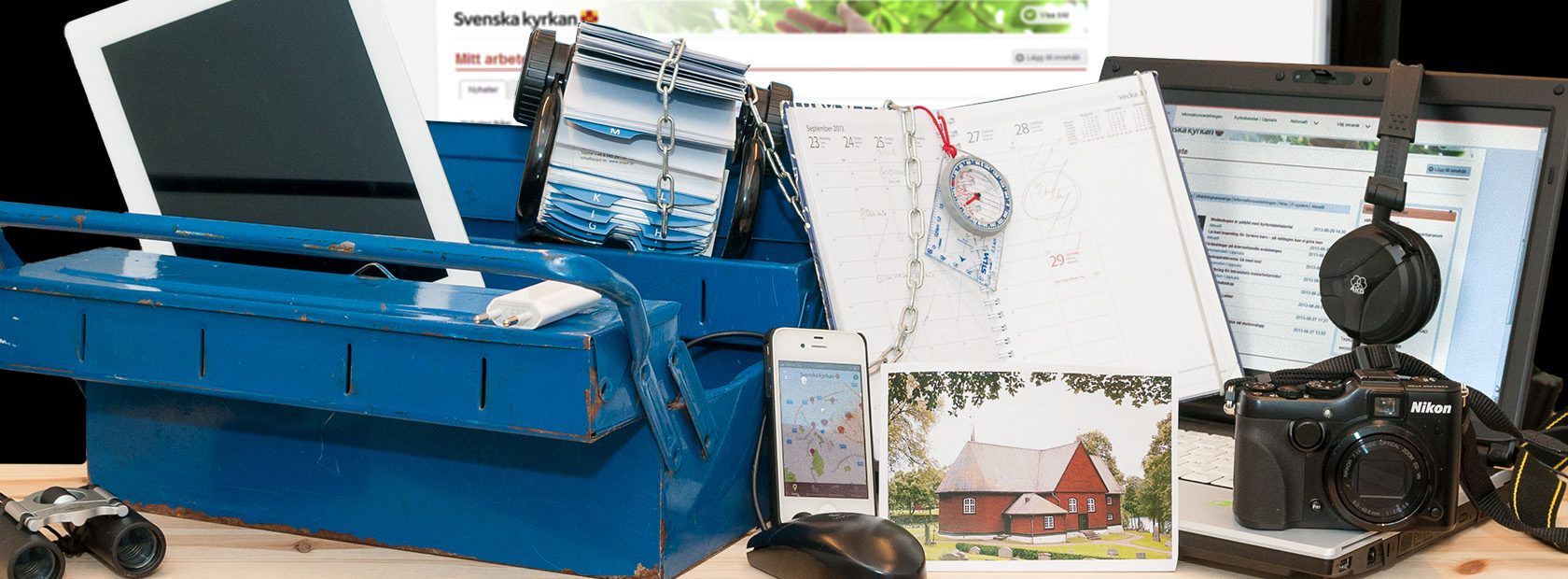 En blå verktygslåda med kikare, telefon, kamera, kompass och bilder på kyrkor.